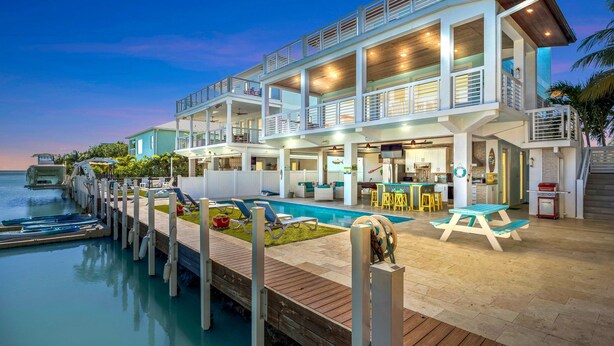 A multi-story waterfront property with a pool, outdoor seating, and a dock. - Luxury Waterfront Oasis w Heated Pool and 50 Dock (Marathon)