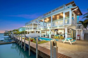 A multi-story waterfront property with a pool, outdoor seating, and a dock. - Luxury Waterfront Oasis w Heated Pool and 50 Dock (Marathon)
