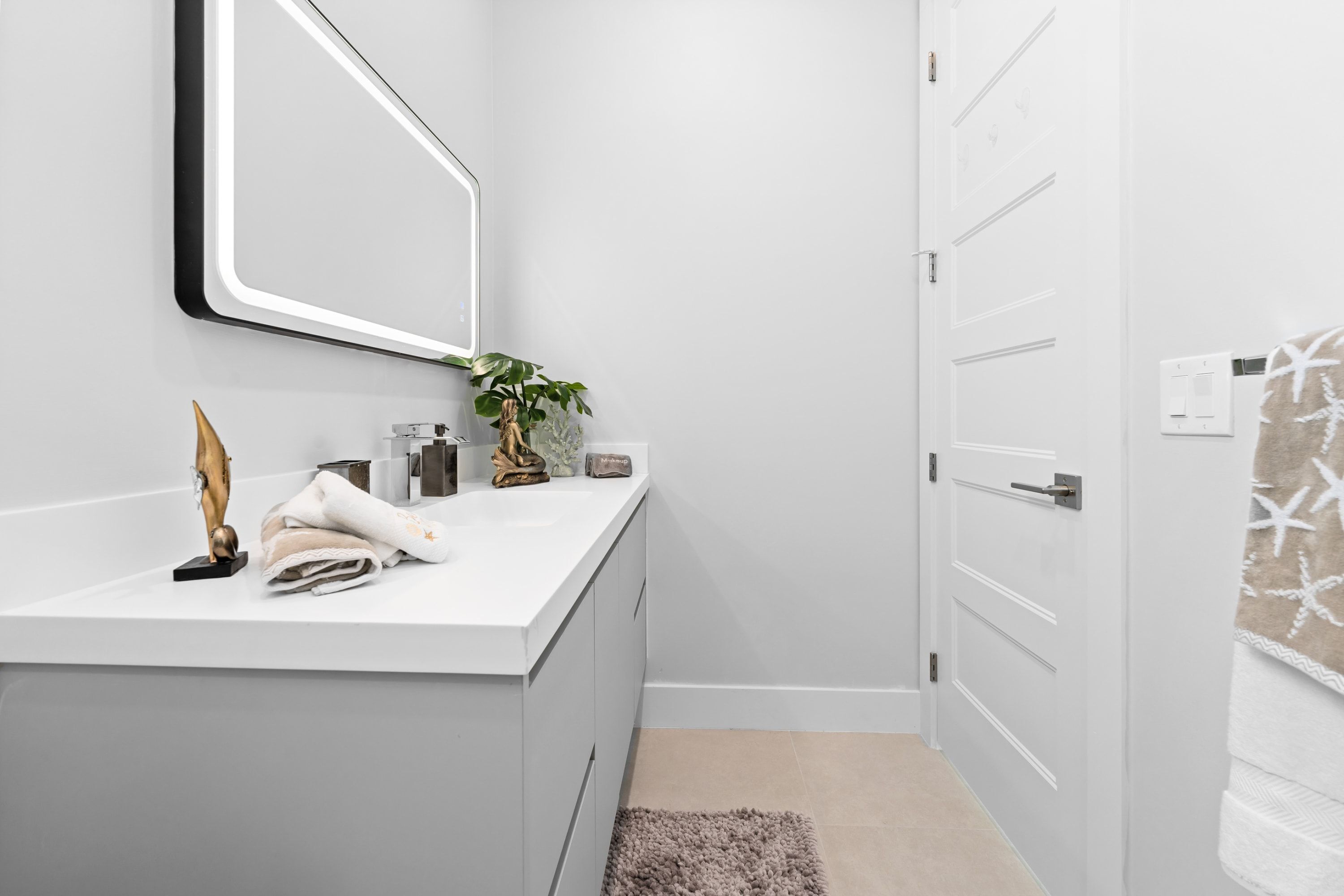 Une salle de bain moderne avec un meuble-lavabo blanc, un grand miroir et une plante.