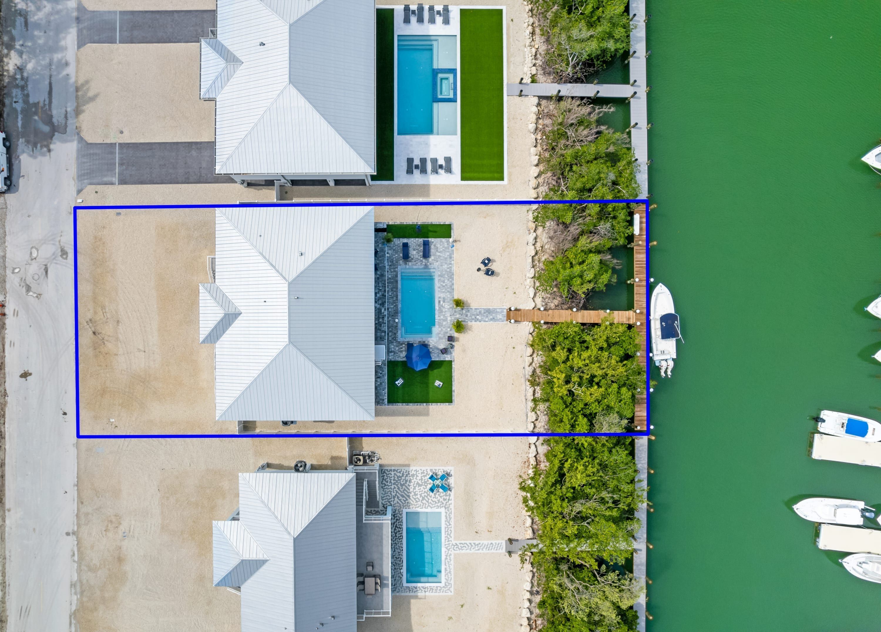 Vue aérienne d’une propriété dotée d’une piscine, d’un patio couvert et d’un quai avec des bateaux.