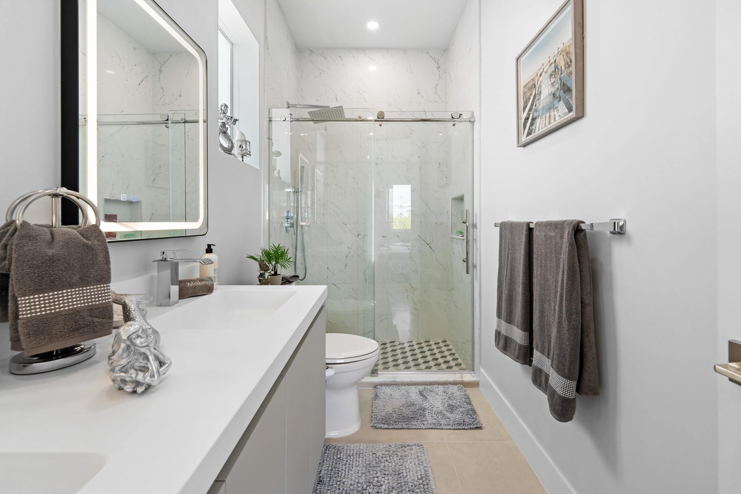 A modern bathroom with a glass shower enclosure, a white sink, and a large mirror.