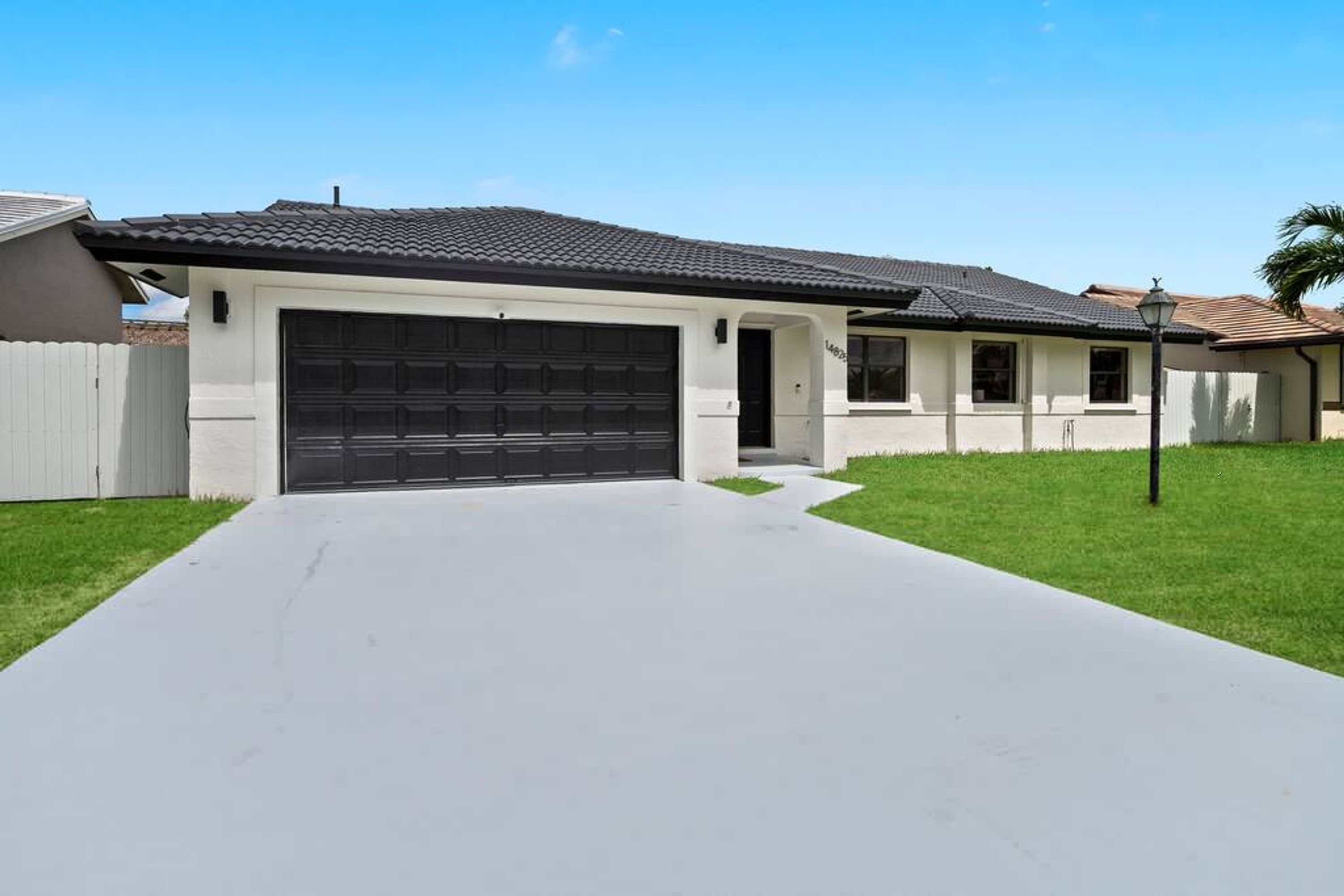 Een gelijkvloers huis met garage, voortuin en lantaarnpaal.