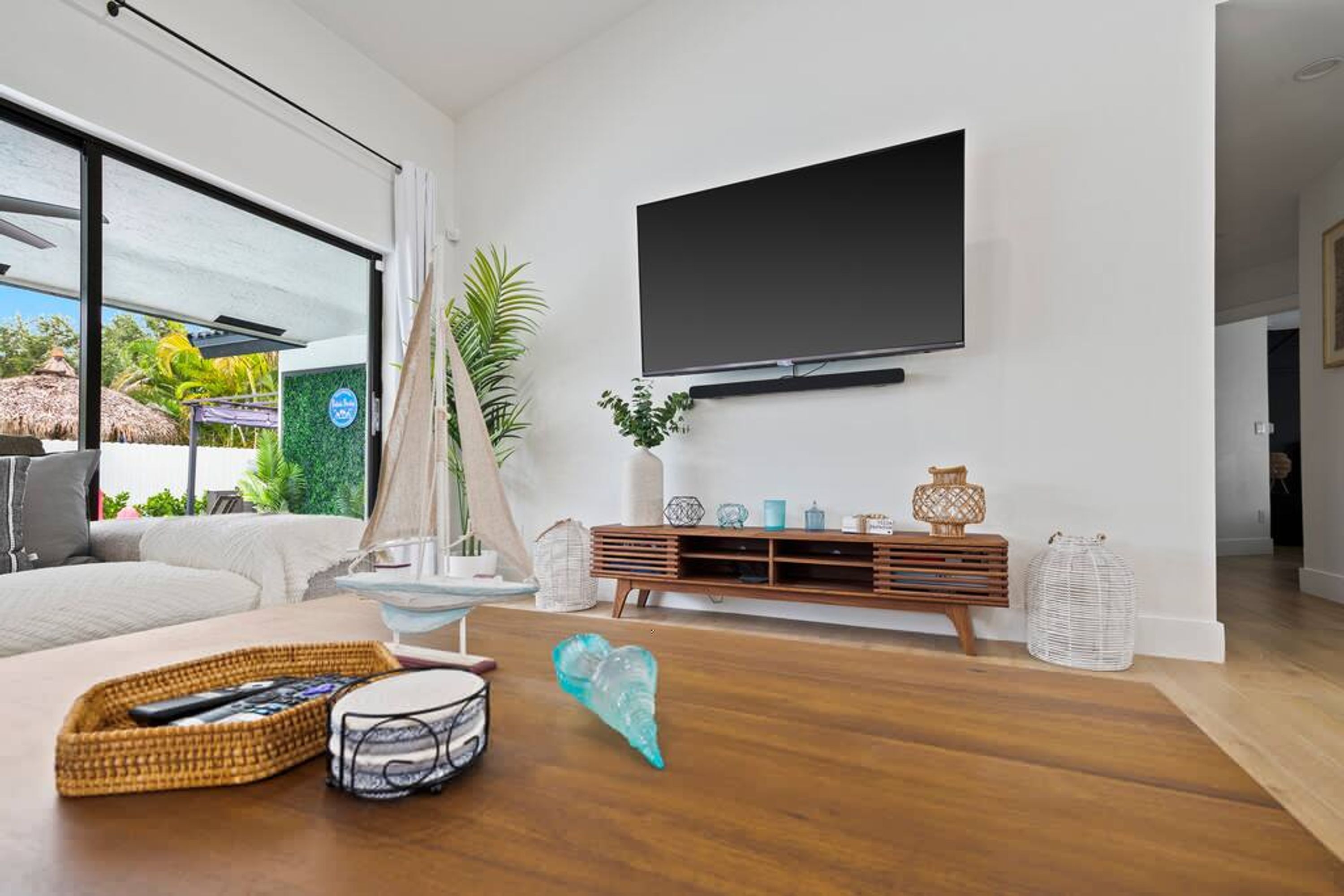 A modern living room with a large TV, wooden flooring, a sofa, and a dining area.