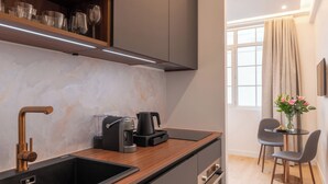 Una cocina moderna con un lavaplatos integrado, una cafetera y un comedor con mesa y sillas.