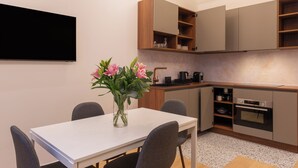 Una cocina moderna con una mesa de comedor y sillas, un jarrón con flores y armarios empotrados.