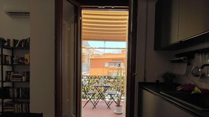 A narrow kitchen with a dining area, a bookshelf, and a view of an outdoor patio with a table and chairs. - New apartment in Rome Trastevere w/ 2 beds, living, excellent transport (Roma)