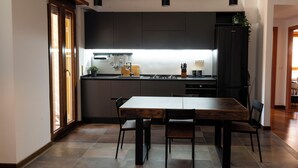 A modern kitchen with dark cabinetry, a wooden dining table, and pendant lighting. - New apartment in Rome Trastevere w/ 2 beds, living, excellent transport (Roma)