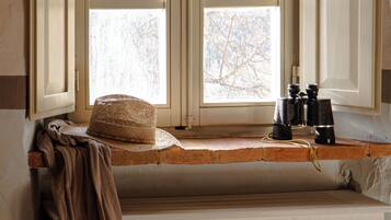 A room with a window featuring two open white shutters, a woven basket, and binoculars on the windowsill.