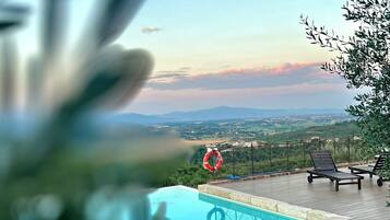 A poolside area with a view of distant mountains, a lifebuoy, and lounge chairs.