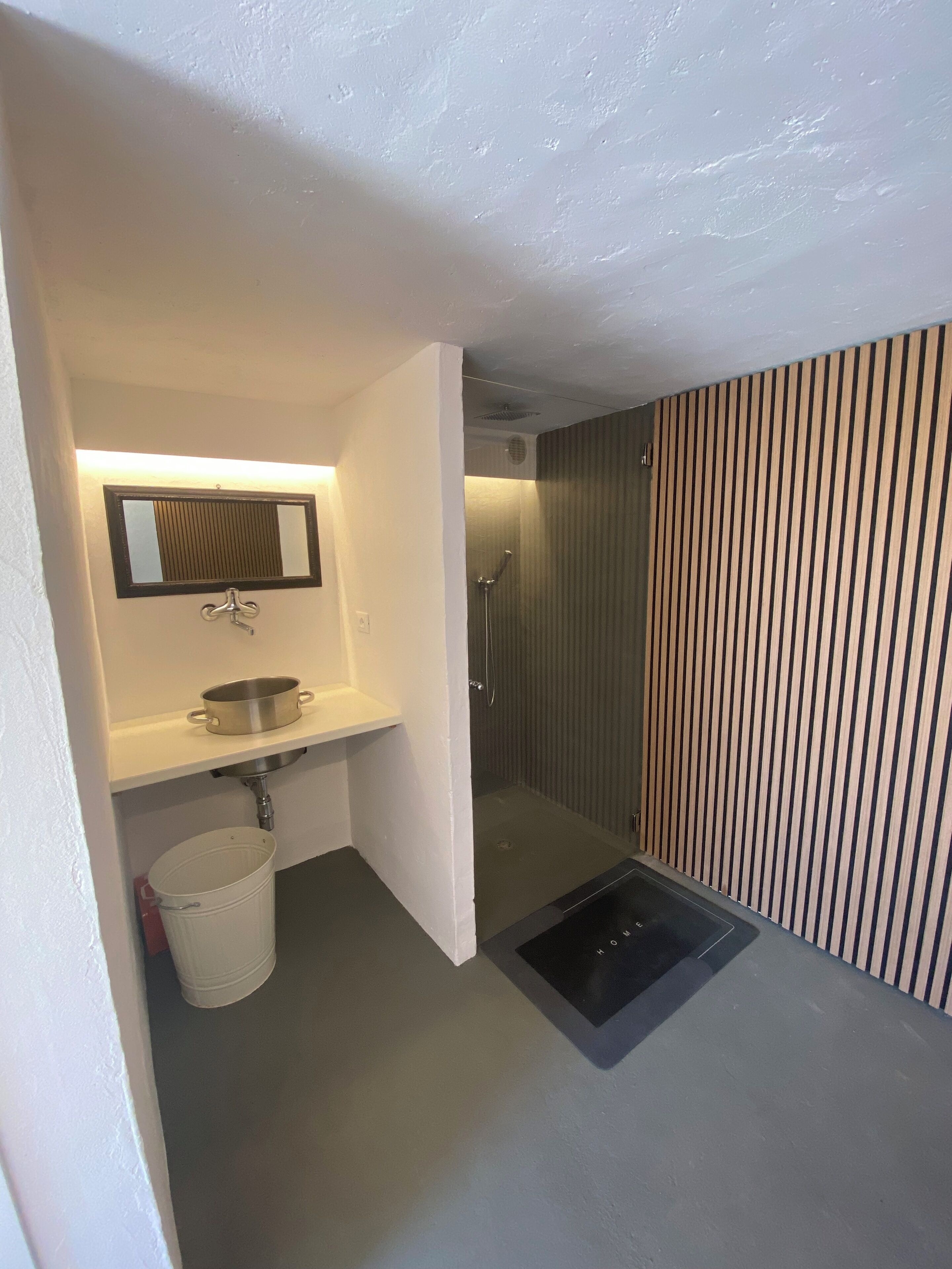 A compact bathroom with a sink, mirror, and shower.