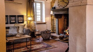 A cozy living room with a fireplace, a clock, and a sofa. - Podere Cavalbianco (Monte San Savino)