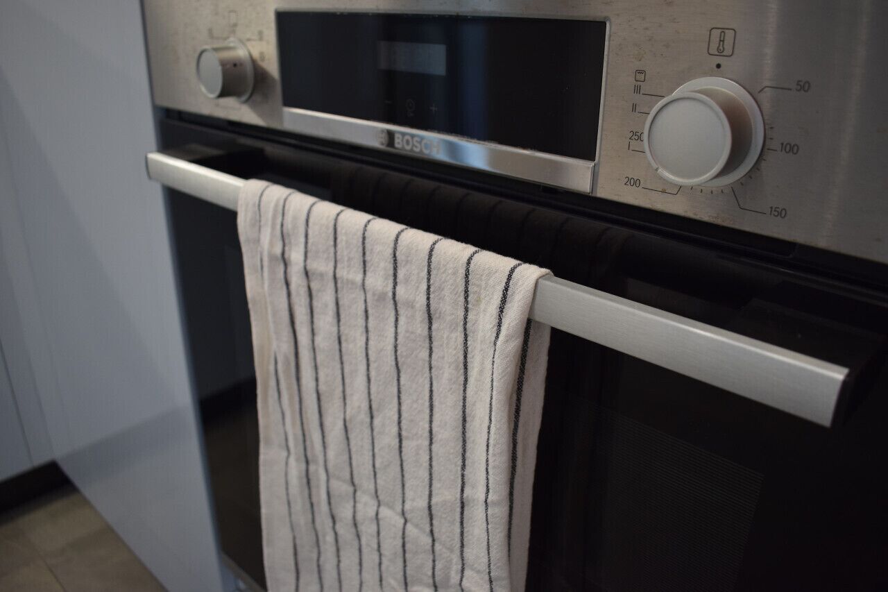 Een keuken met een Bosch oven, een bedieningsknop en een handdoek aan de ovenhandgreep.
