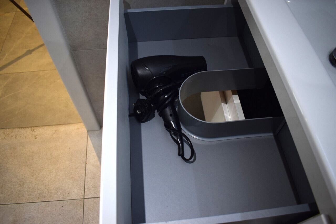 Un cajón con un secador negro y un recipiente gris.