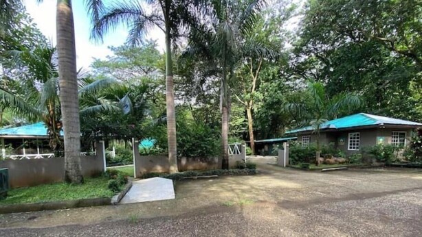 A gravel driveway leading to a gated entrance with a small concrete ramp. - Rupia Apartment.

 (San Pedro Town)