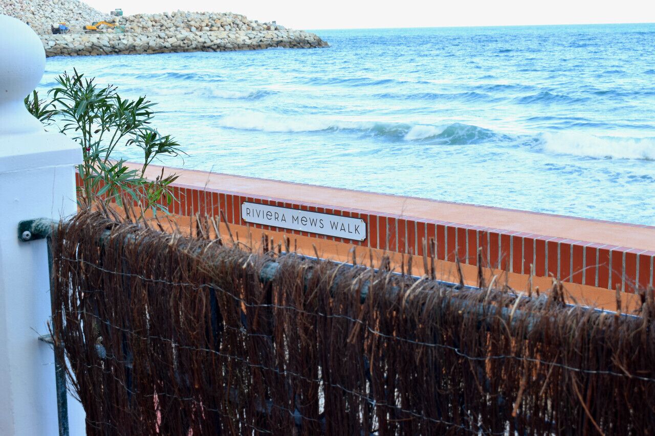 Vista del océano con un letrero que dice "RIVIERA Mews Walk".