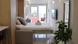 Une chambre moderne avec un lit, un bureau et un balcon doté d’une rambarde rouge.
