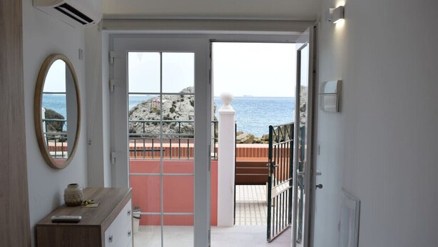 Une pièce dotée d’une porte-fenêtre coulissante donnant sur un balcon avec vue sur la mer.
