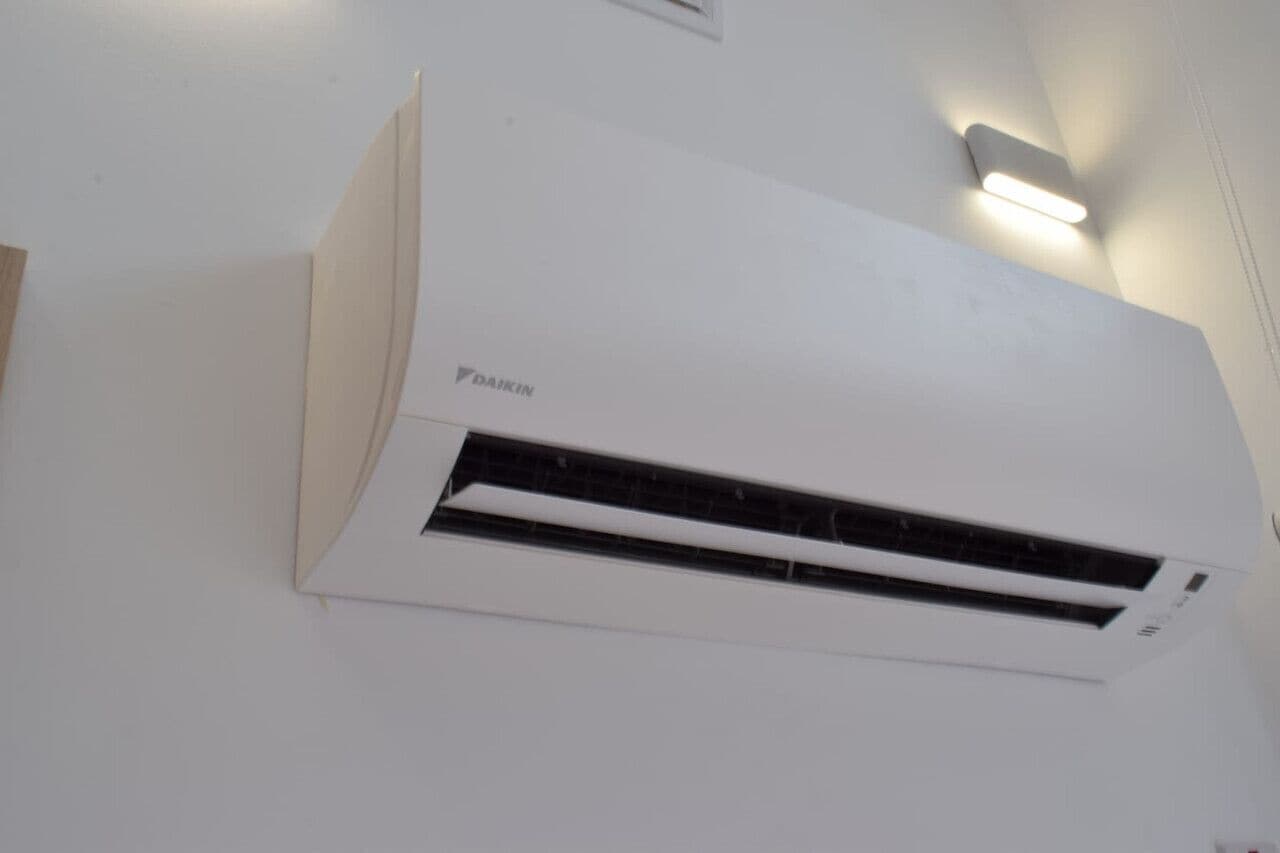 Un aire acondicionado blanco instalado en la pared, con el nombre de la marca 'DAIKIN' a la vista.