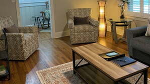 Ein Wohnzimmer mit gemusterten Möbeln, einem Holztisch, einer Uhr und einem Deckenventilator.