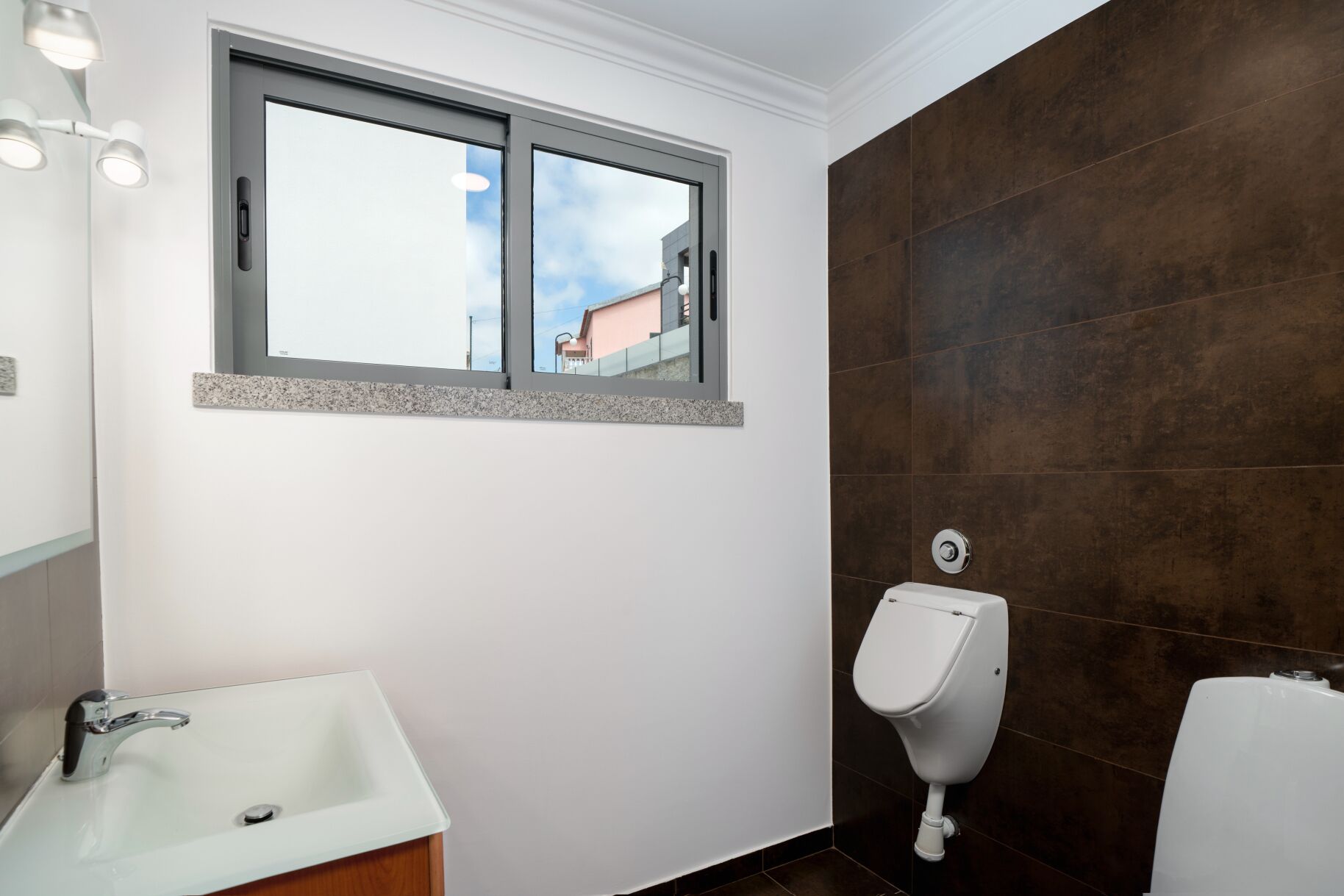 Ein Badezimmer mit Fenster, Waschbecken und einer Urinalschale.