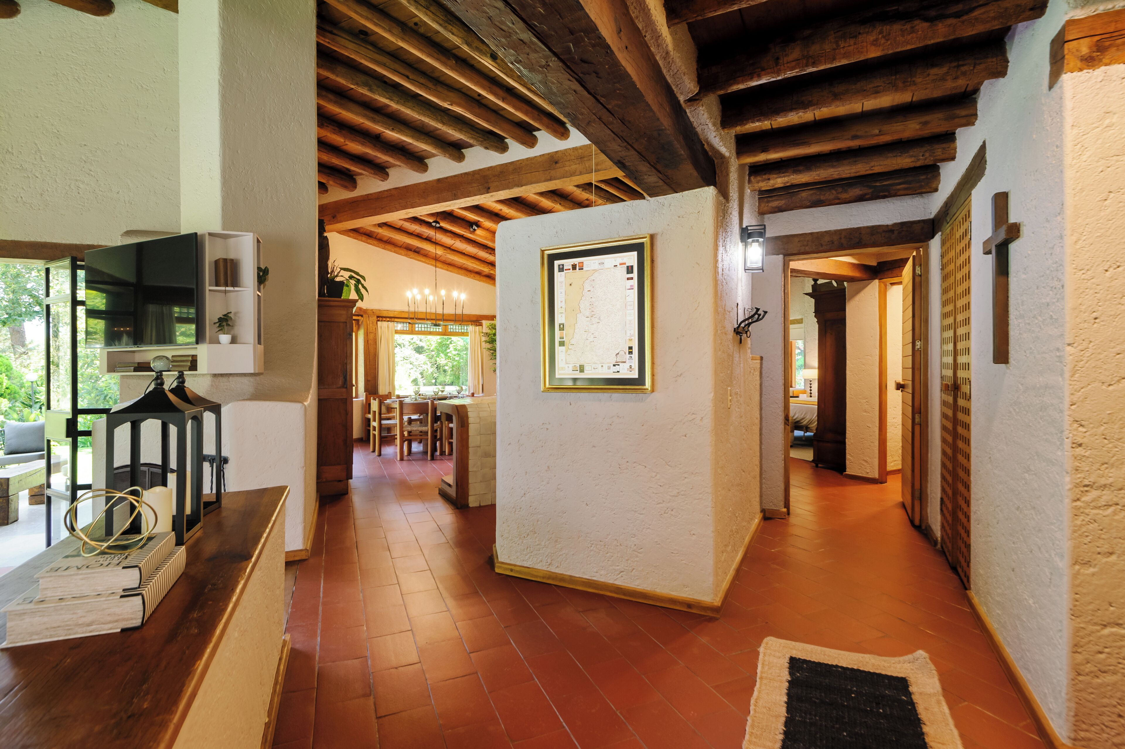 A hallway with wooden beams, a tiled floor, and a framed map on the wall.