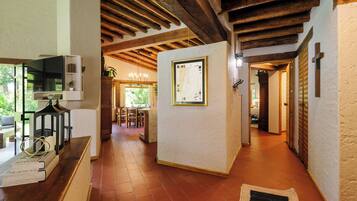 A hallway with wooden beams, a tiled floor, and a framed map on the wall.