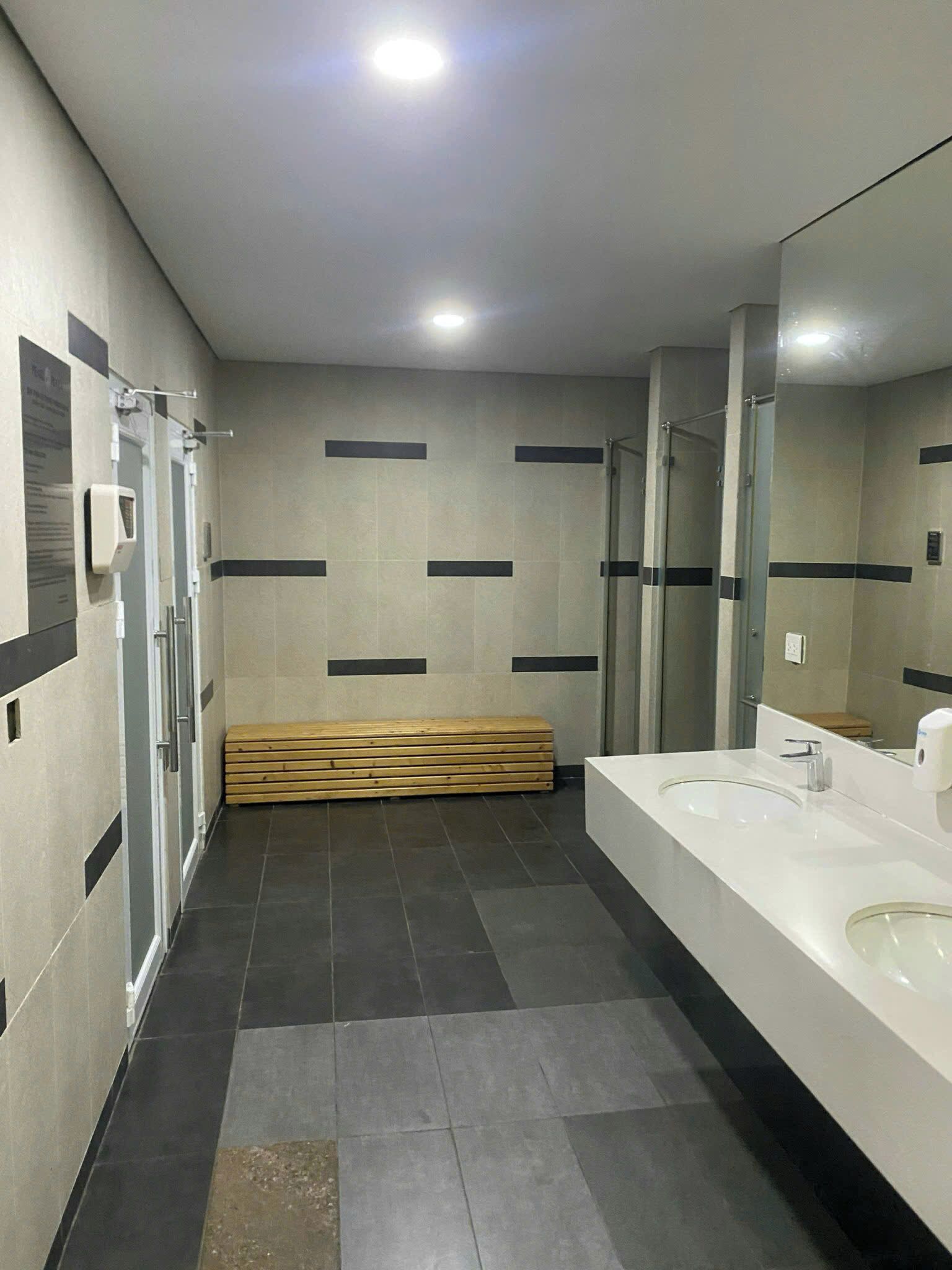 Un baño moderno con un tocador amplio, un banco y zona de ducha.