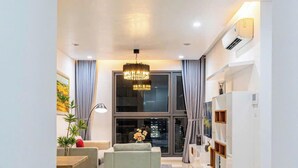 A modern living room with a sofa, a dining table, and a chandelier.