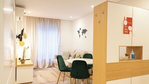 A modern dining area with a round table, green chairs, and a wooden sideboard. - N&N Home Porto, your home in the center of Porto.  (Porto)