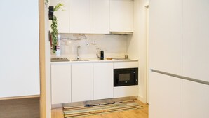 A compact kitchen with white cabinets, a built-in microwave, and a small sink. - N&N Home Porto, your home in the center of Porto.  (Porto)