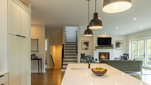 A modern kitchen with a large island, pendant lighting, and a fireplace.