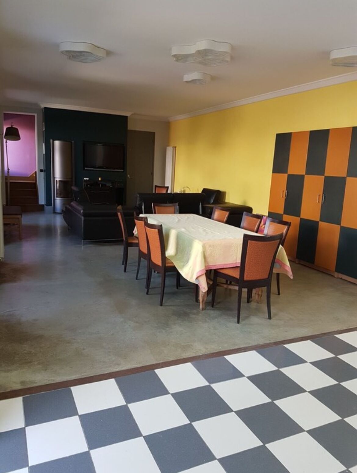 A dining area with a checkered floor, a table set with chairs, and a wall with a checkered pattern.