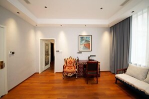 Ein Zimmer mit Holzboden, einem Sofa, einem Schreibtisch mit Stuhl und einem Gemälde an der Wand.