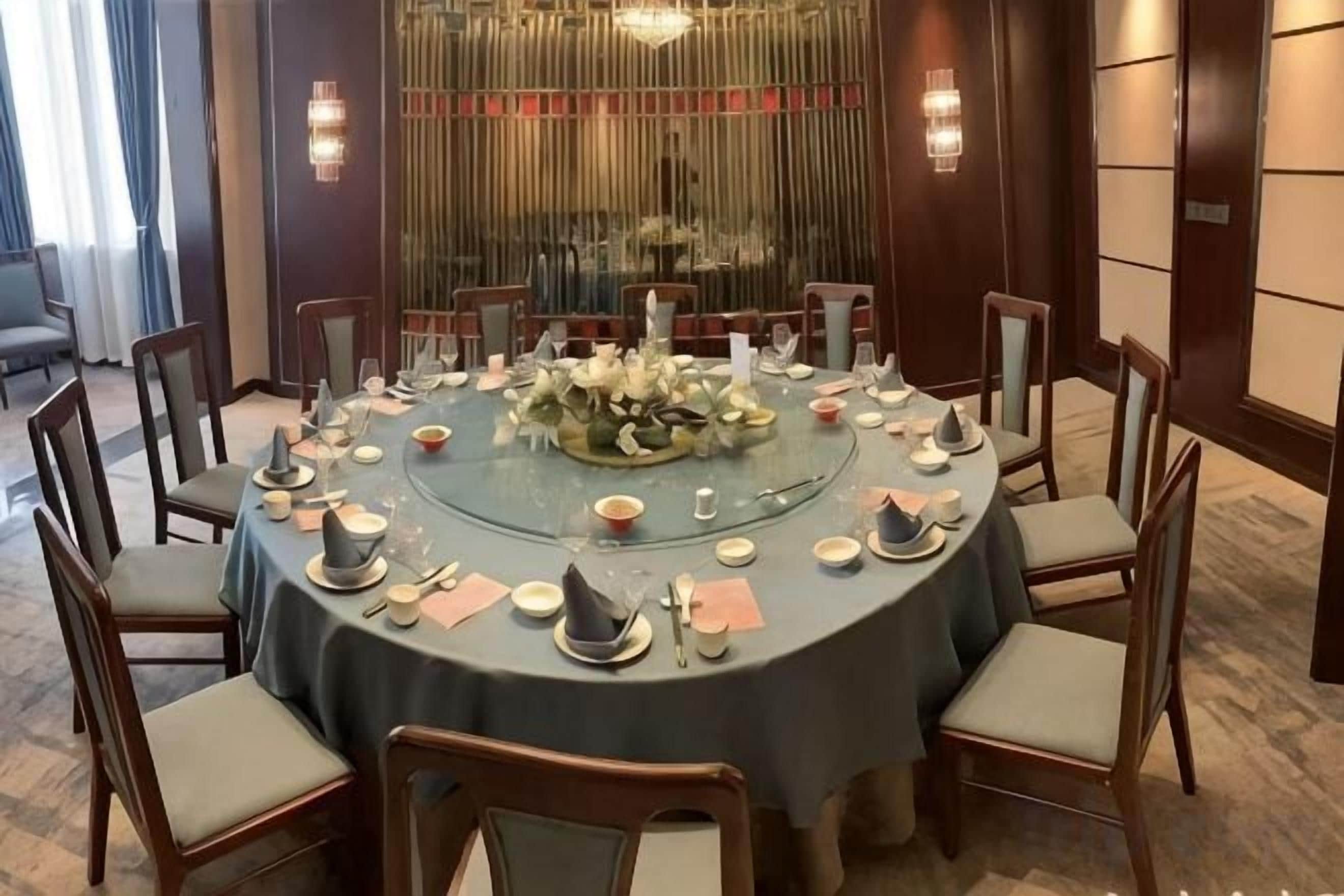 A round dining table set with chairs, a floral centerpiece, and tableware.