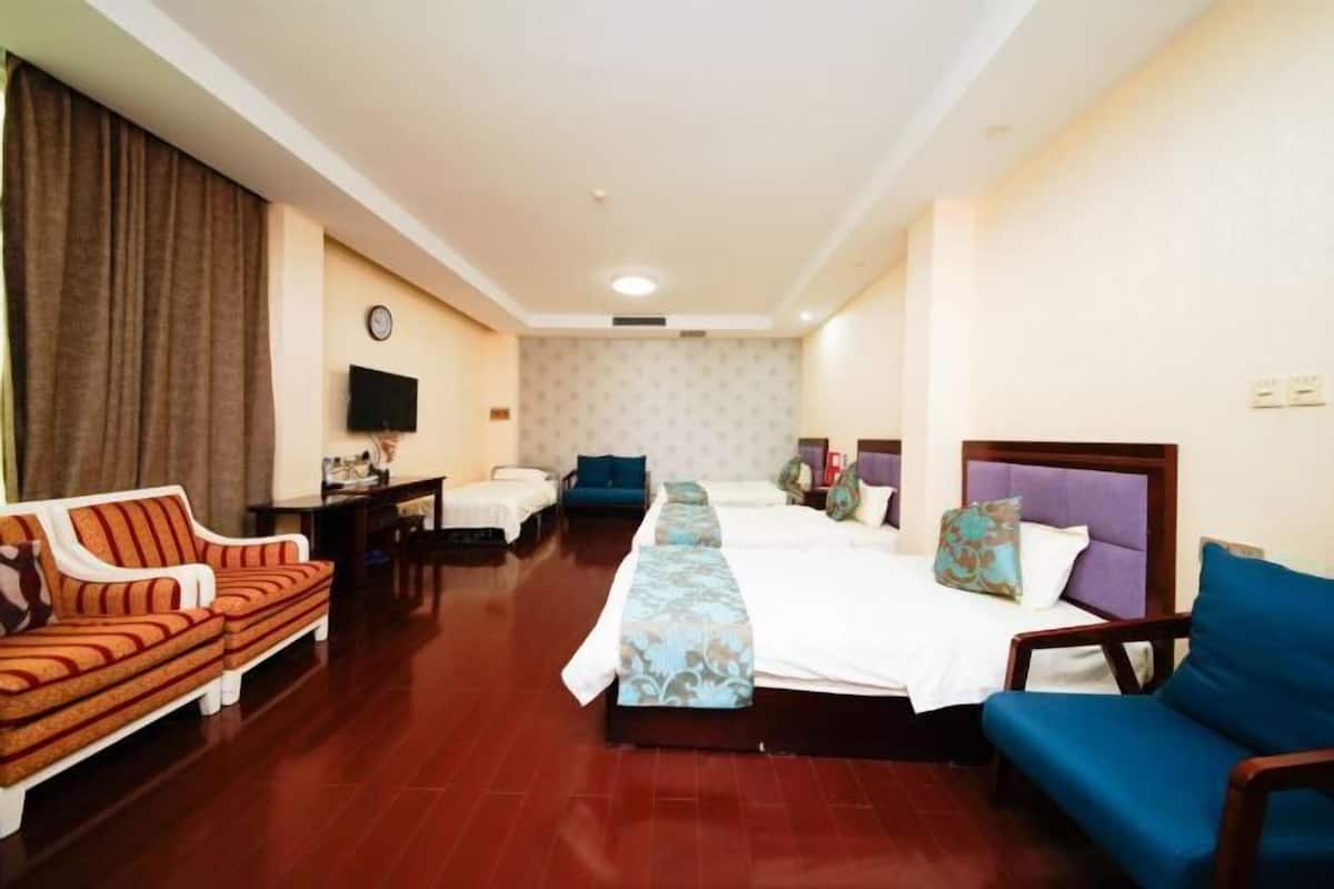 A hotel room with a large bed, a sofa, a chair, a TV, and a desk.
