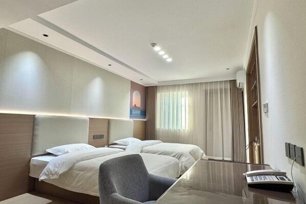 Ein Hotelzimmer mit zwei Betten, einem Schreibtisch mit Telefon und einem großen Fenster mit Vorhängen.