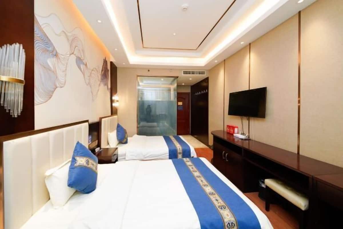A hotel room with two beds, a television, and a large artwork on the wall.