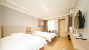Una camera d'albergo con due letti, una scrivania con televisore e un quadro appeso al muro.