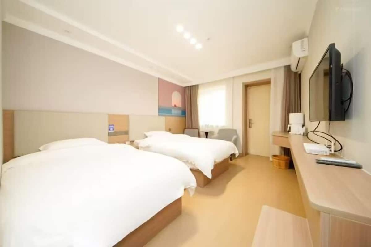 A hotel room with two beds, a desk with a TV, and a painting on the wall.