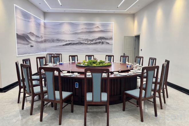 A conference room with a round table, chairs, and a large painting on the wall.
