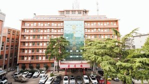 Ένα πολυώροφο κτίριο με μια κεντρική γυάλινη πρόσοψη και μια κόκκινη τέντα.