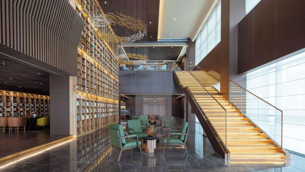 Eine moderne Lobby mit Treppe, Sitzgelegenheiten und einer Bücherwand.