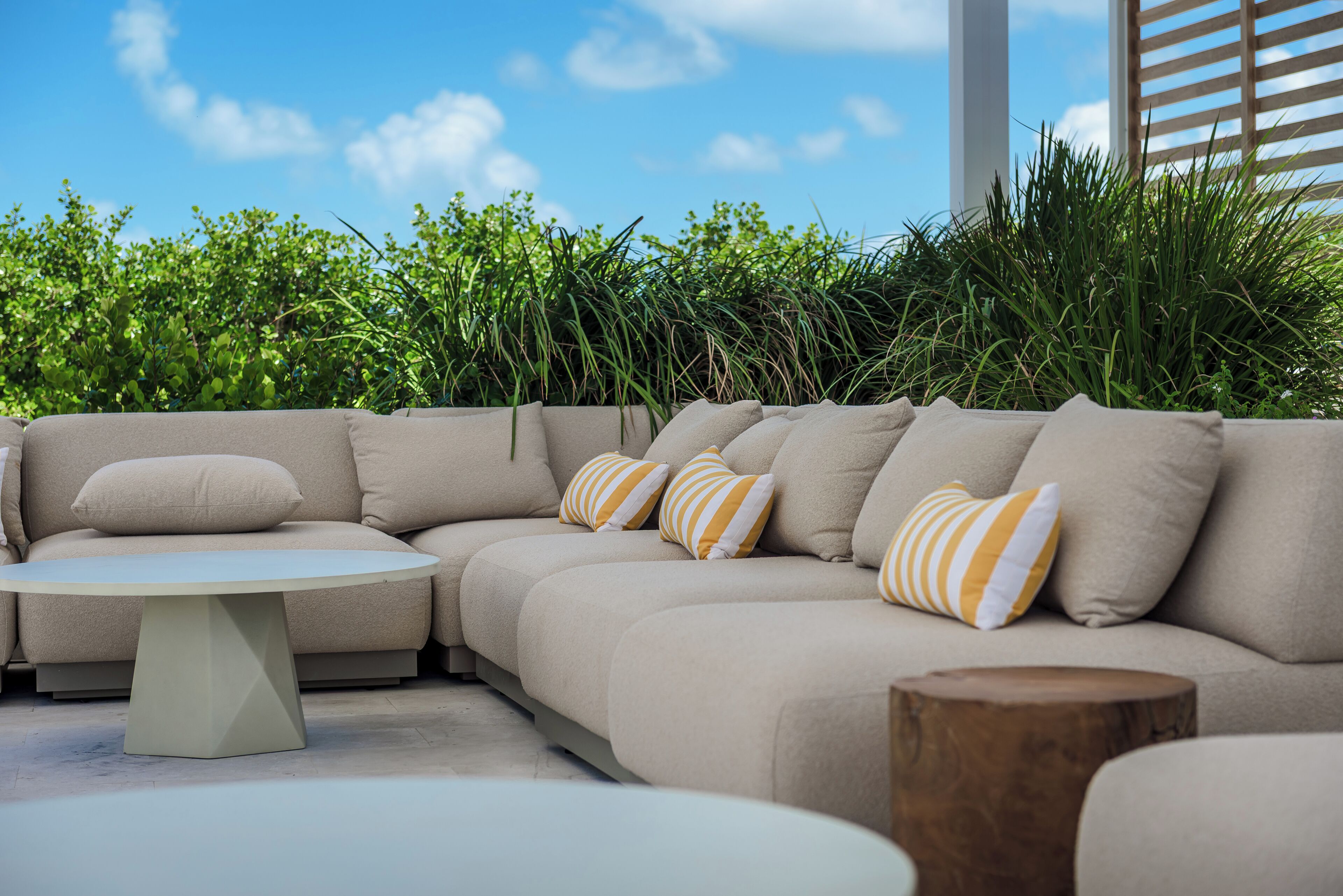 An outdoor seating area with a sofa, a round table, and a wooden stump.