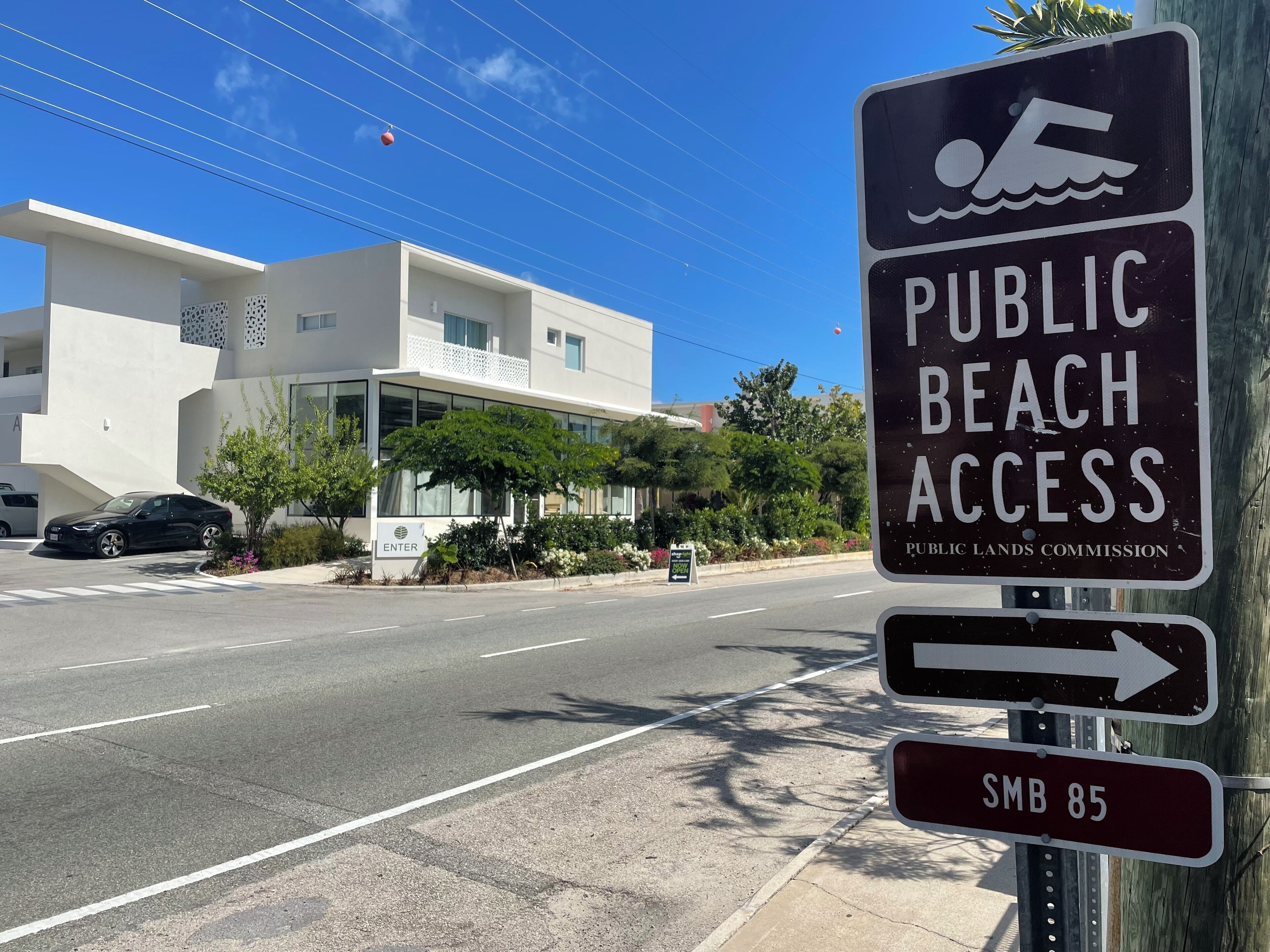 A sign indicating public beach access and a direction to SMB 85.