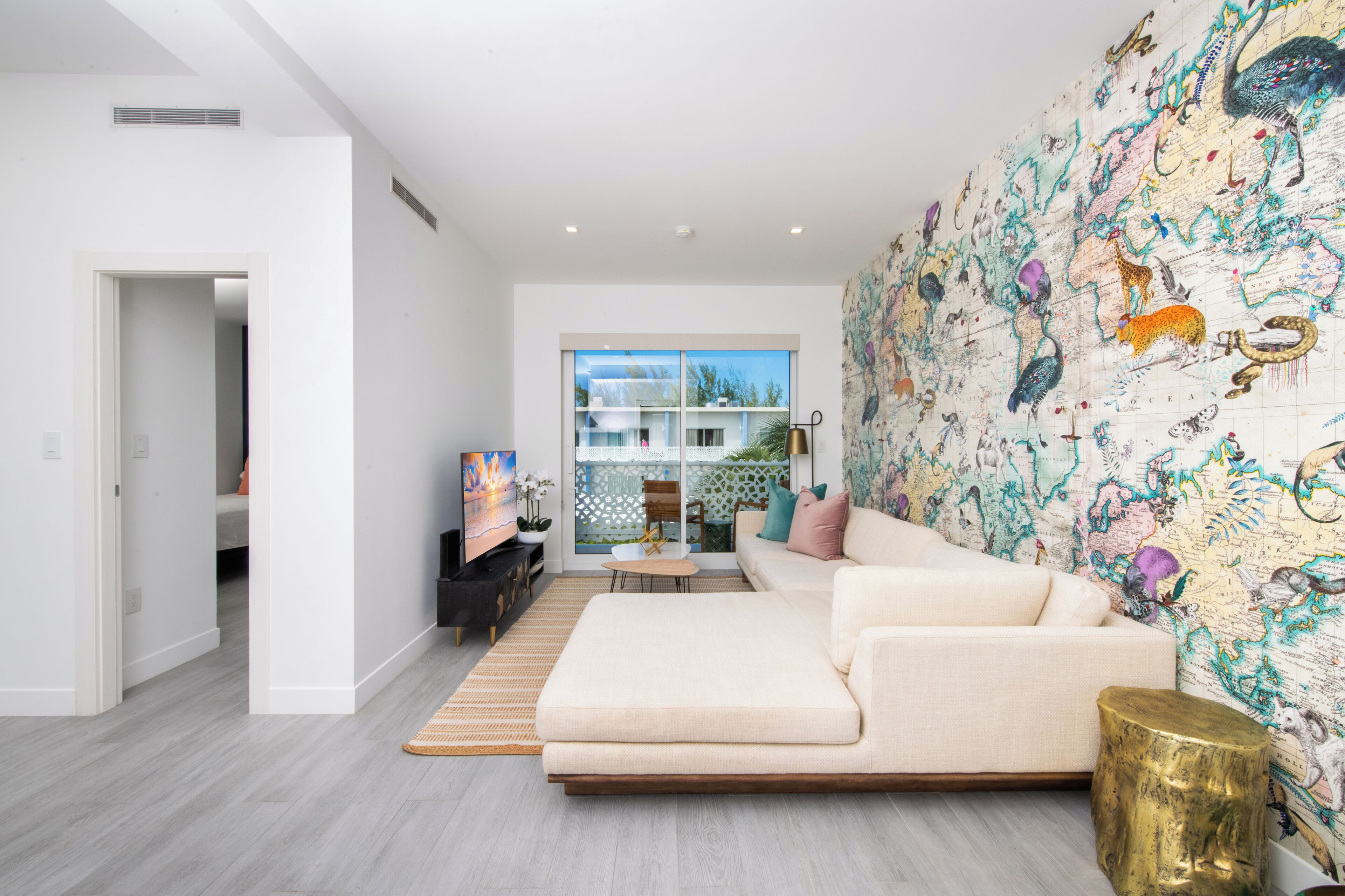 Una sala moderna con un amplio sofá modular, un mapa decorativo de pared y vistas al exterior a través de un gran ventanal.