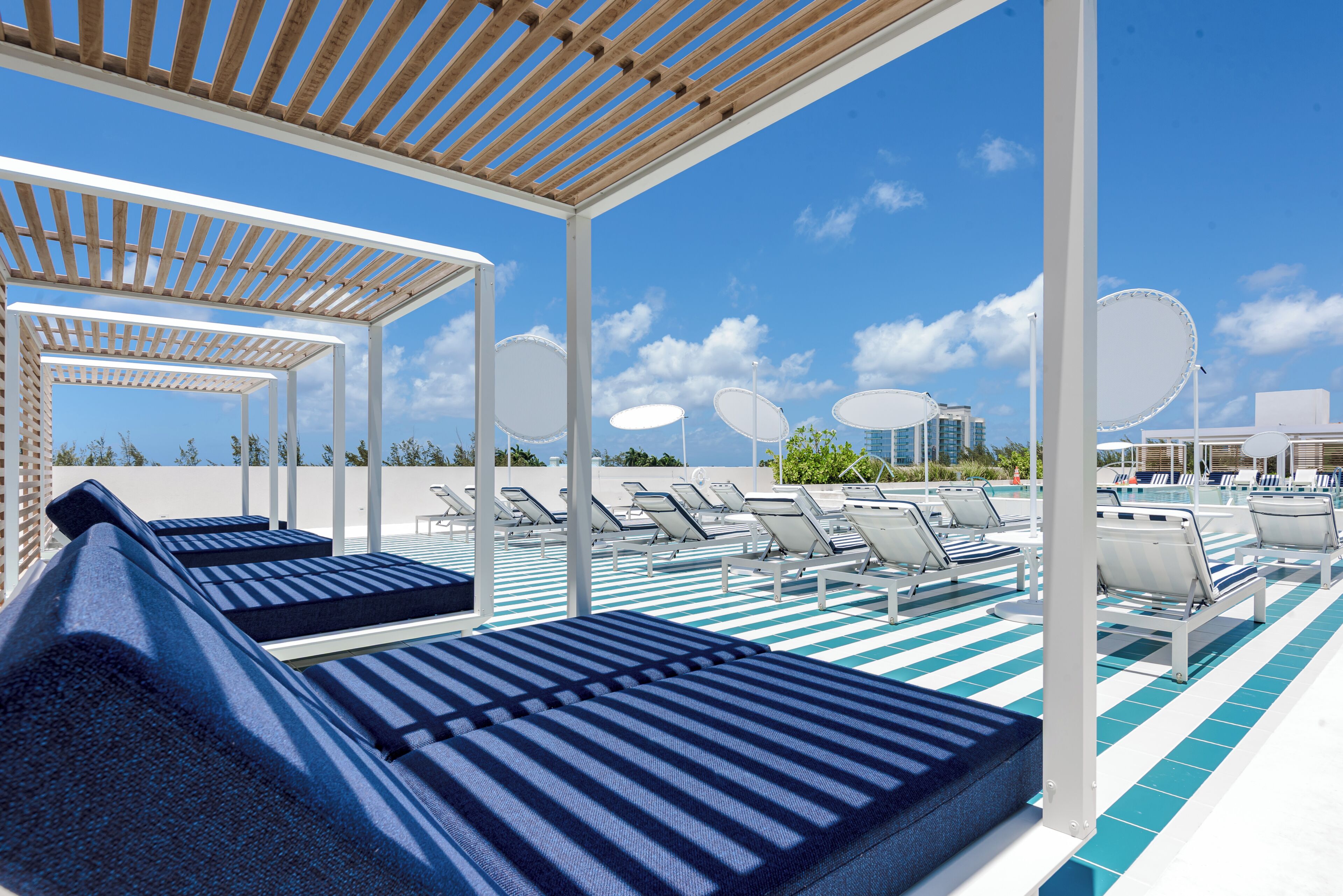 Ein Poolbereich mit Liegestühlen, einer Pergola und Blick auf den Himmel.