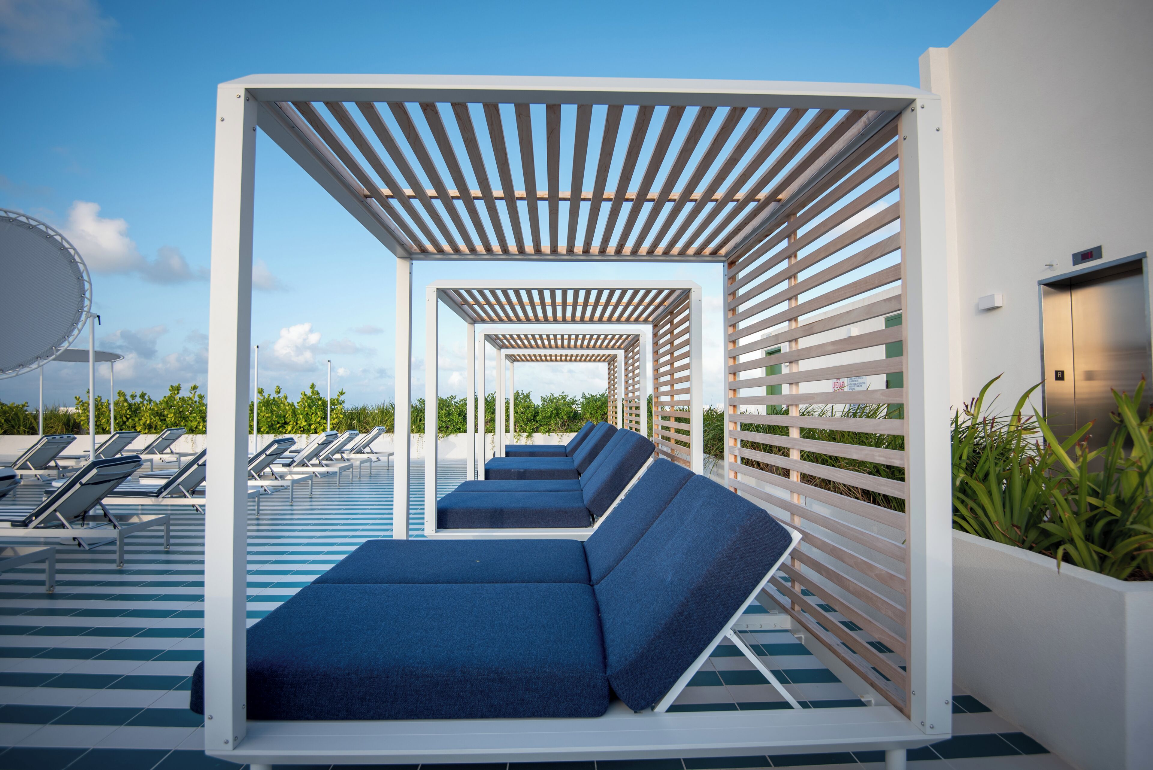 Un área de piscina en la azotea con sillones de descanso y una pérgola.