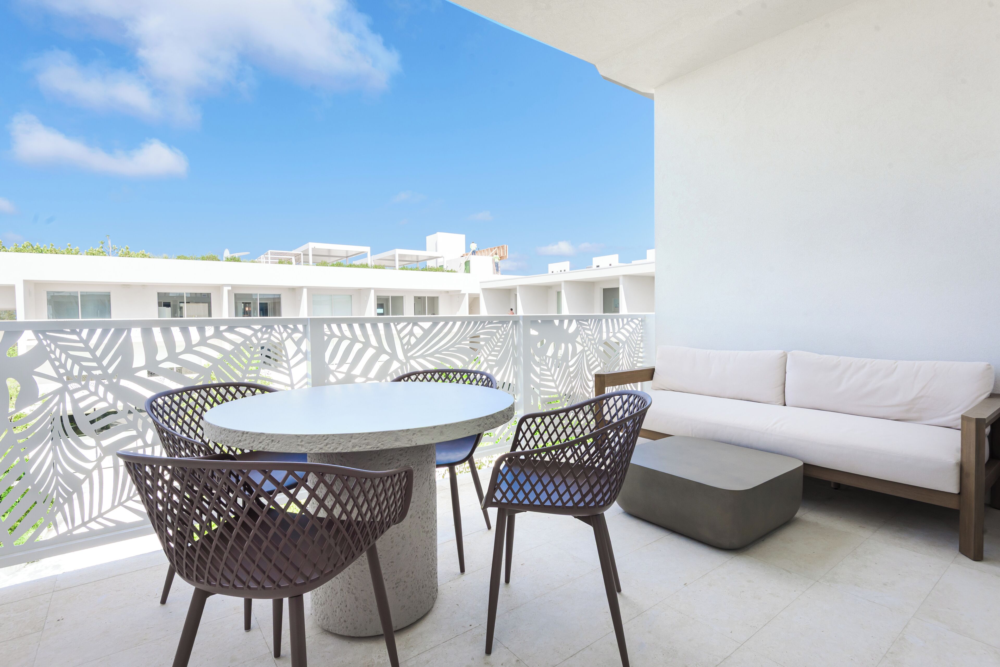 Ein Balkon mit einem runden Tisch, Stühlen und einer Couch.