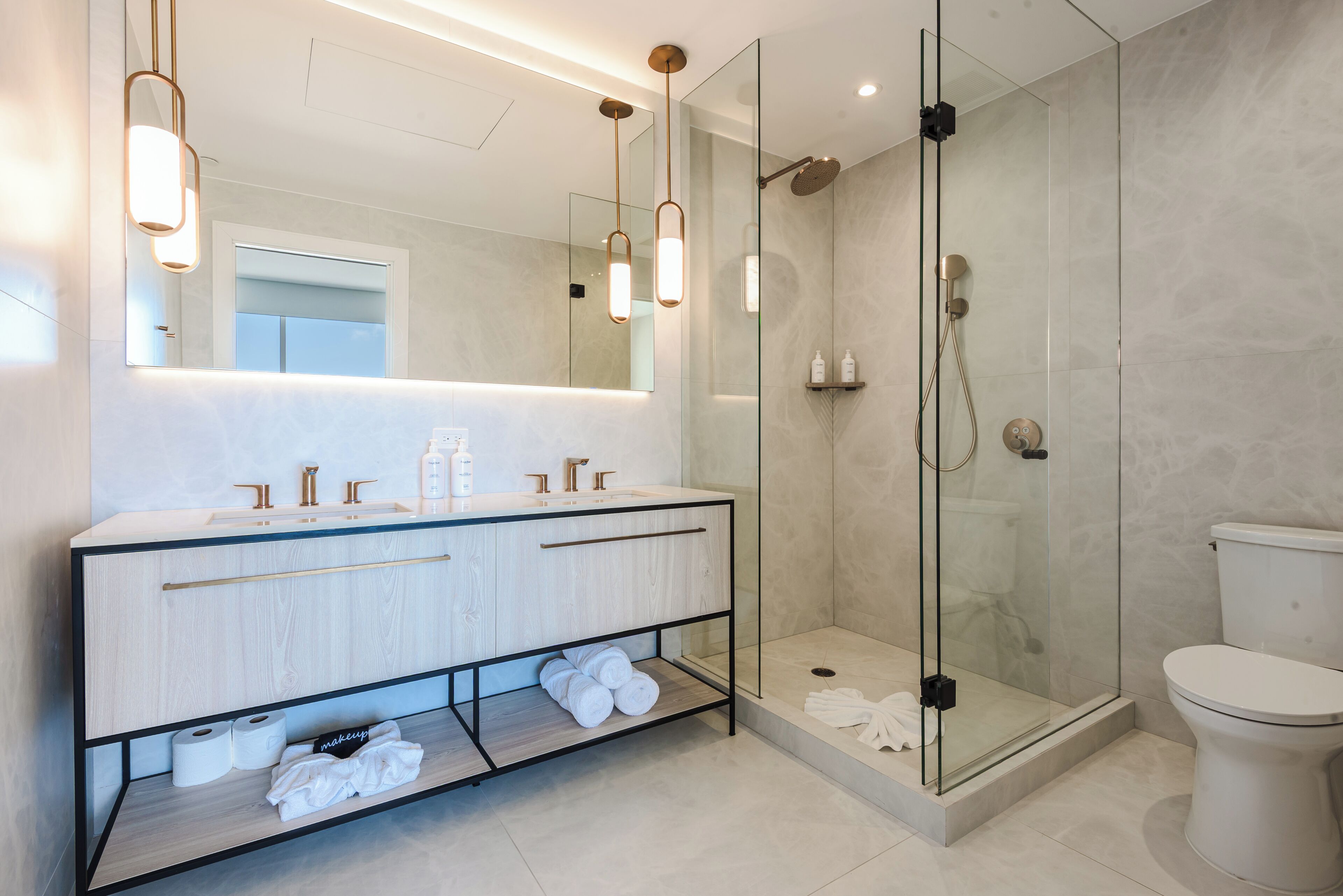 A modern bathroom with a glass-enclosed shower, a vanity with a mirror, and a toilet.