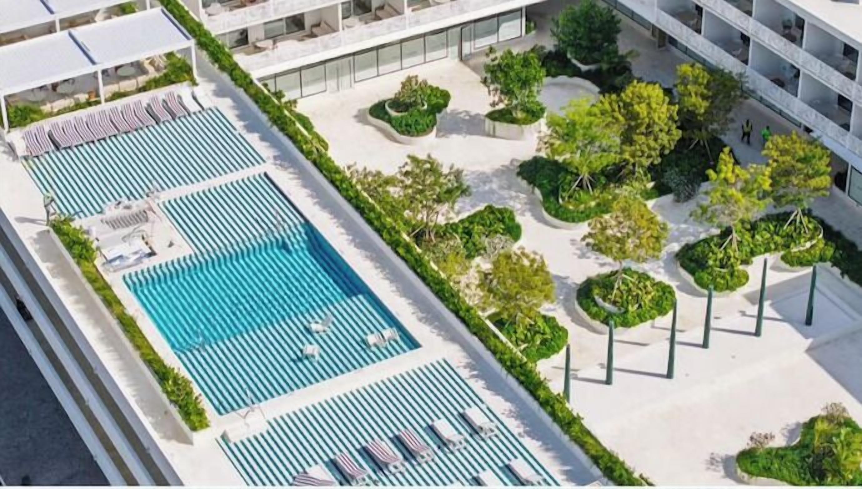 A rooftop pool area with multiple swimming pools and lounge chairs.